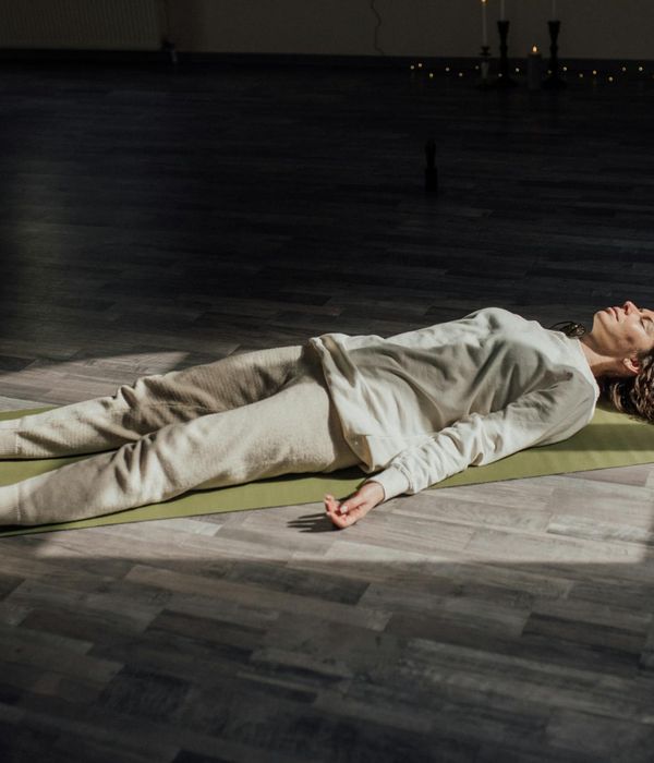 Woman practicing breathing exercise in a serene setting with fuchsia light.